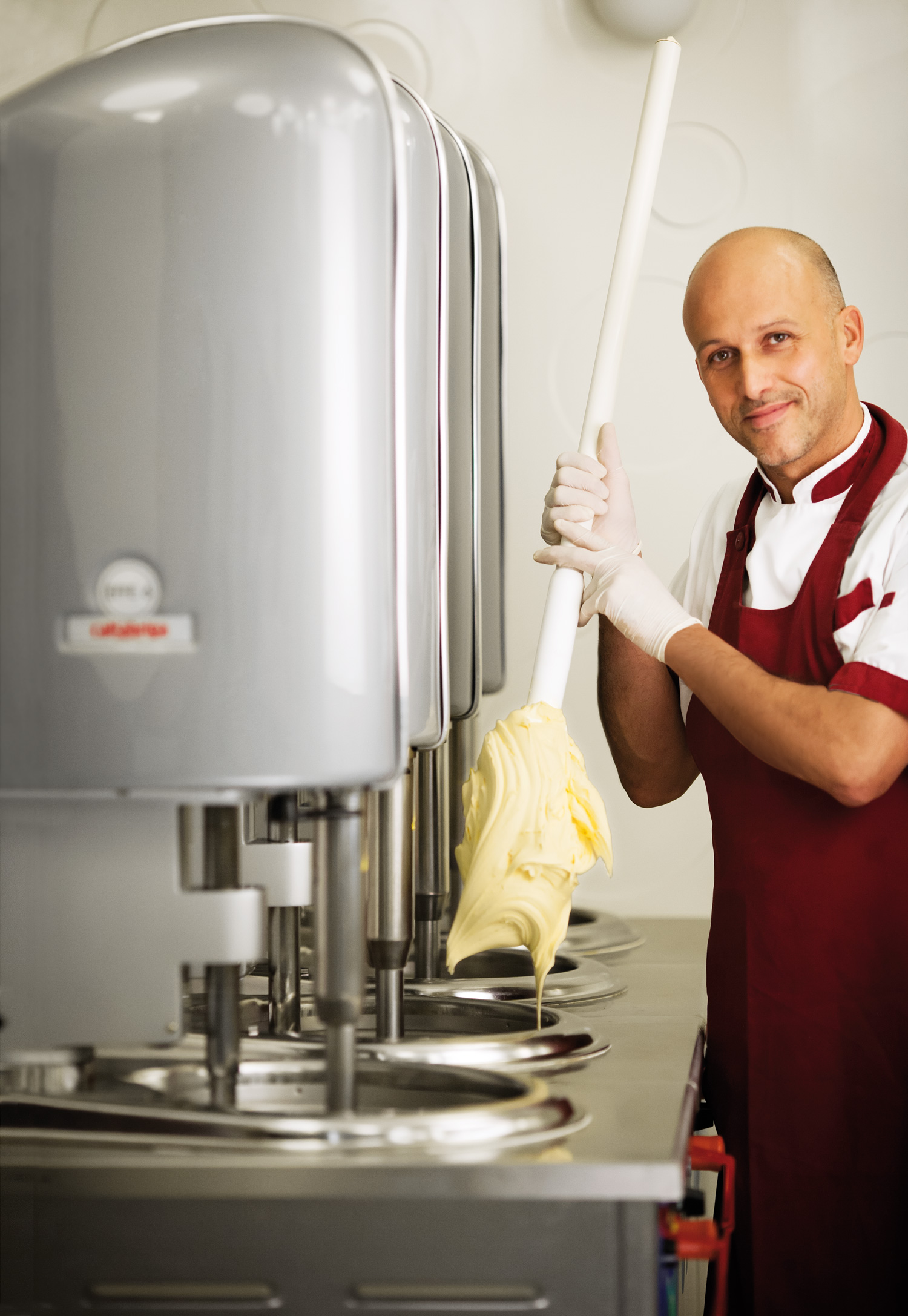 A gelato maker lifting a paddle of freshly churned gelato from a Cattabriga Effe vertical batch freezer