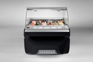 A modern black gelato display case with a glass top, showcasing several flavors of colorful gelato arranged in metal trays against a plain, light gray background.