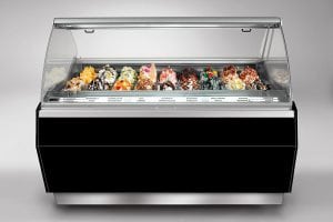 A display case filled with assorted gelato flavors, each topped with various fruits, nuts, and sauces, arranged in rows inside a modern, black and silver refrigerated counter.