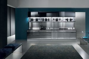 A modern kitchen with sleek stainless steel cabinets and appliances, open shelving with bottles and utensils, blue walls, a patterned rug, a bench with cushions, and bright, even lighting.