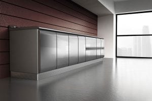 A modern, sleek gray storage cabinet stands against a maroon wood-paneled wall in a minimalist room with large windows overlooking a cityscape. The floor is smooth concrete, and the atmosphere is bright and clean.