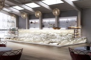 Modern cafe interior with a glowing onyx counter, glass display cases with pastries, shelves of glasses and bottles, hanging spherical lights, and large windows letting in natural light.