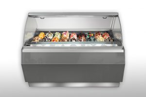 A modern gelato display case filled with various colorful gelato flavors, each topped with decorative ingredients, set against a plain white background.