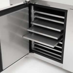 A stainless steel cabinet with its door open, showing several empty, removable metal trays or shelves inside. The cabinet appears clean and industrial, likely used for food or medical storage.
