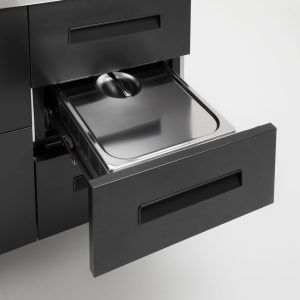 A sleek, modern kitchen drawer is open, revealing a stainless steel container with a lid inside, set against a minimalist white background.